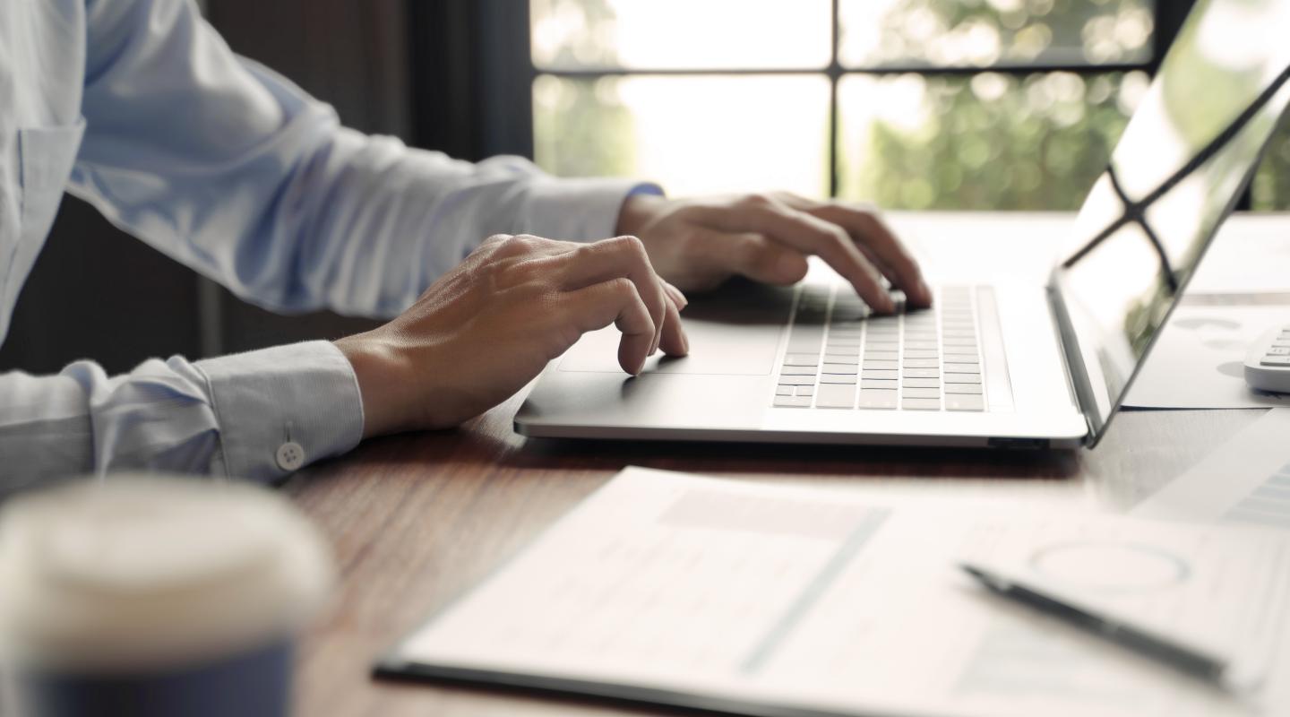 Business professional male with hands typing on a laptop
