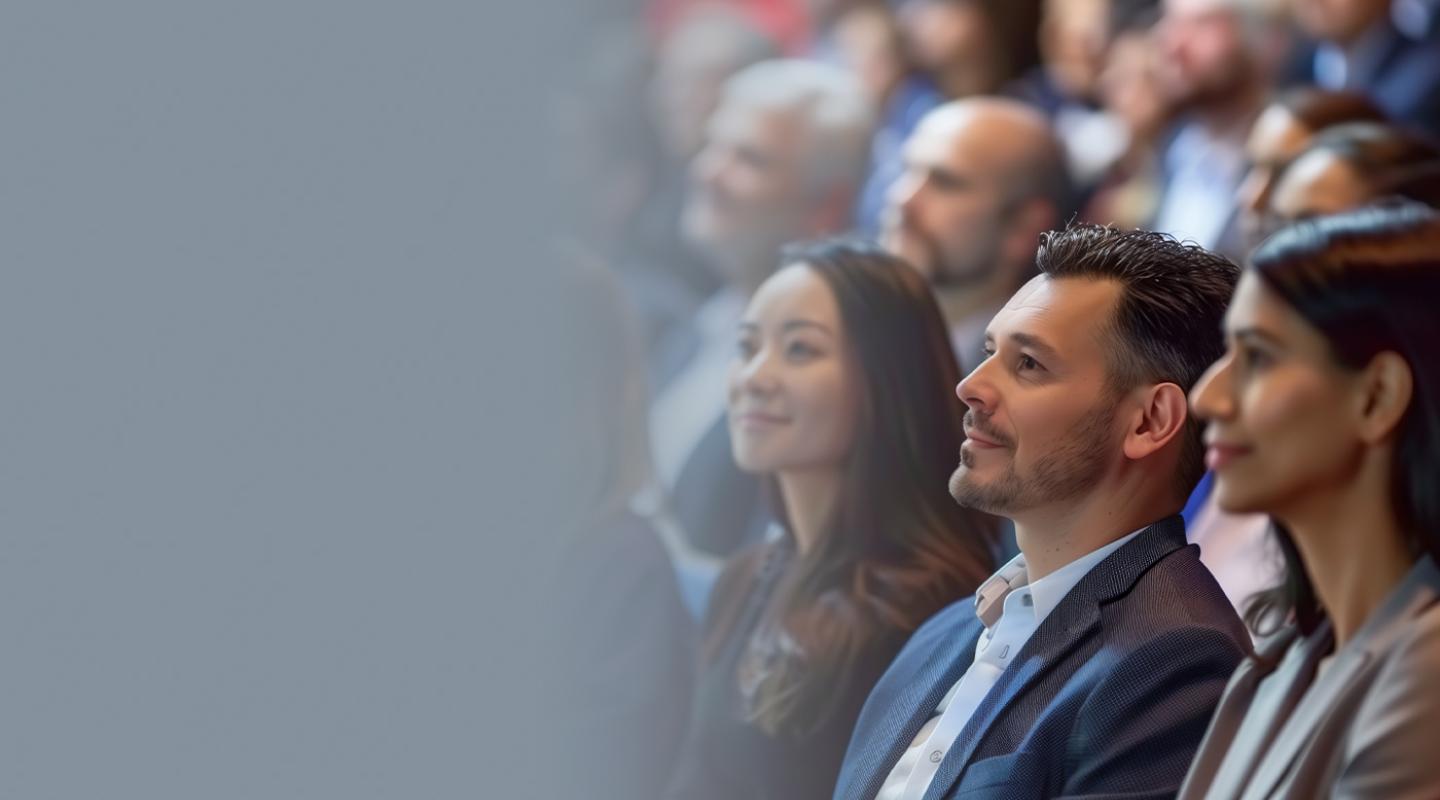 Banner image of a crowd of business people watching a speaker and smiling