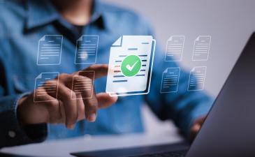 Business man at his laptop pointing at a document with checkmark