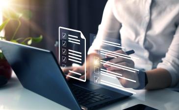 Businesswoman at her laptop holding her pen to a checklist image