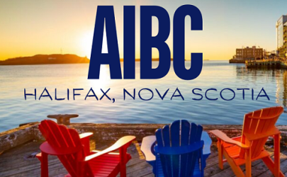 Sunset at a city waterfront with two red chairs, blue text above that says "AIBC" in all caps then "Halifax, Nova Scotia" below