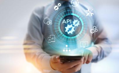 Male in business shirt and tie holding his phone, with a blue 'API' text above the  phone and white icons depicting technology maintenance