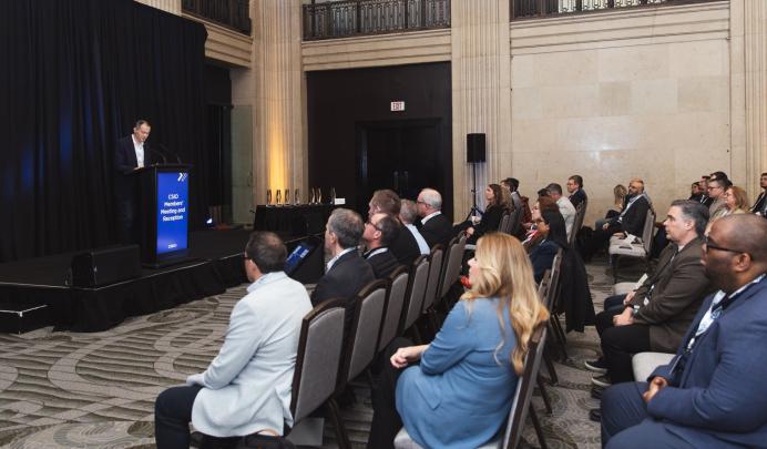 CSIO Board Chair Michael Lin speaking on a podium in front of members in a large banquet hall