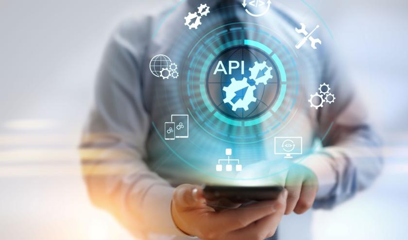 Male in business shirt and tie holding his phone, with a blue 'API' text above the  phone and white icons depicting technology maintenance