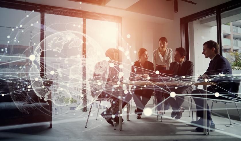 Group of professionals in a glass office in a meeting, with white graphics of a globe, lines and dots representing technology