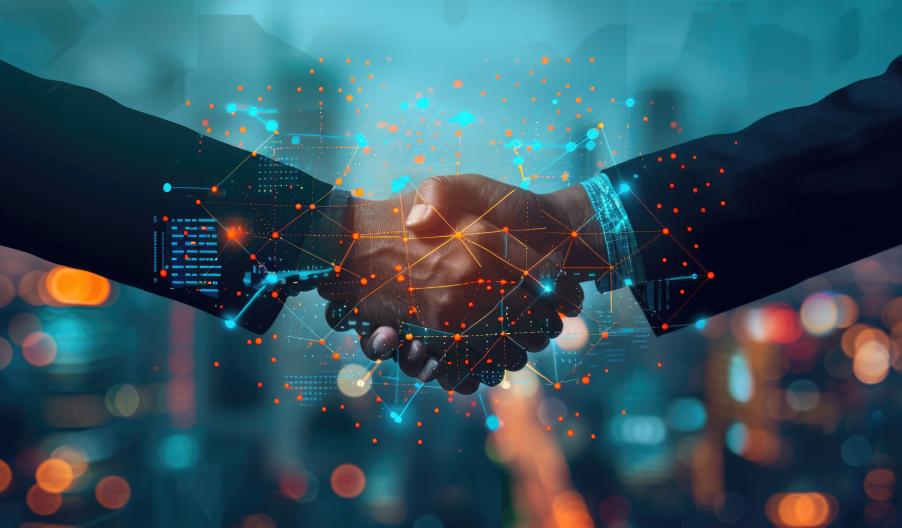 Two professionals shake hands amid digital graphs and colleagues' silhouettes, symbolizing teamwork